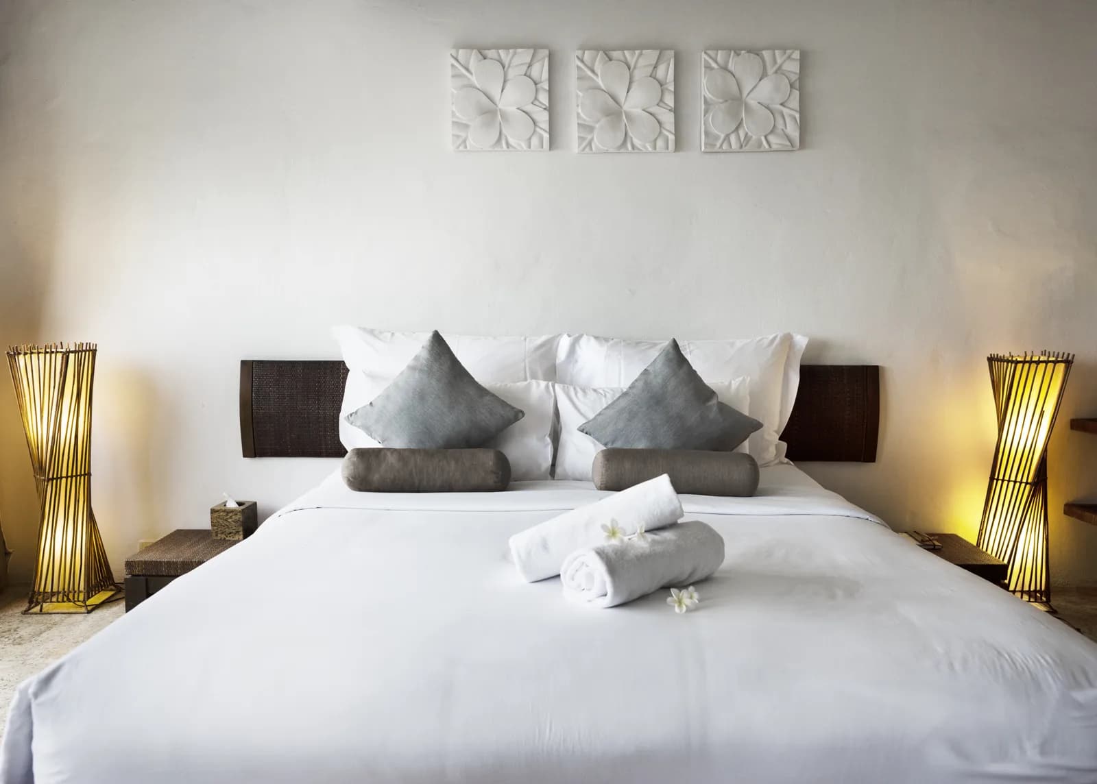 A bright four-star hotel double room with white bedding, cushions and rolled towels between two lamps