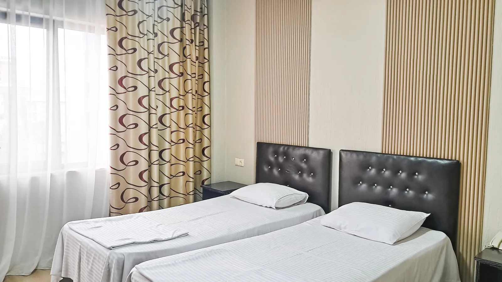 A simple hotel twin room with two single beds and white sheets